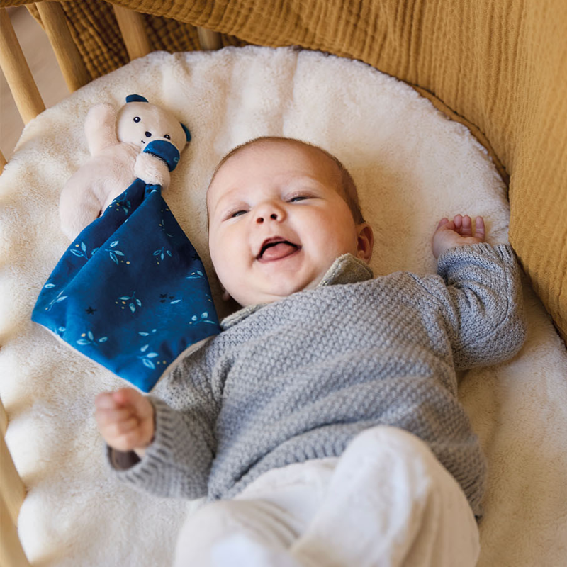 Bebê sorrindo com naninha cachorrinho Carré Douceur azul