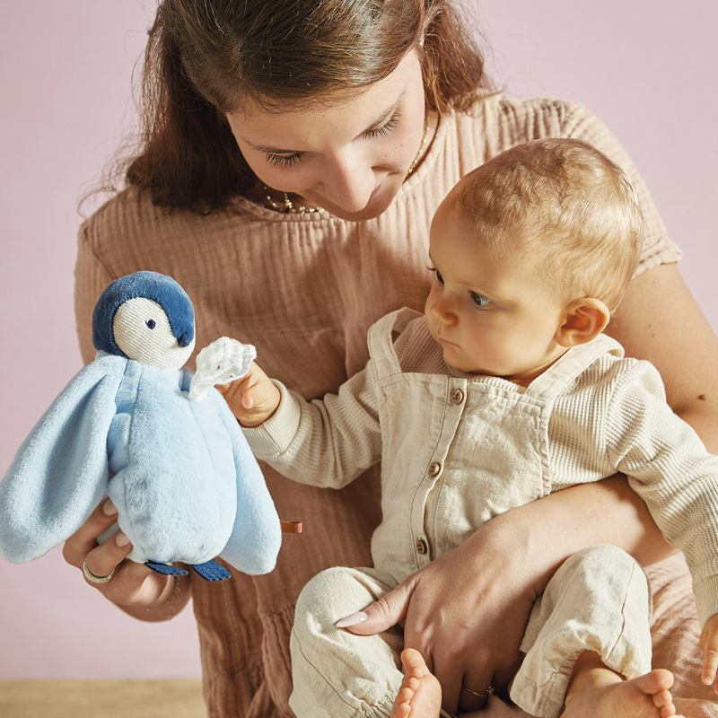 Mãe mostrando pinguim Complices azul ao bebê